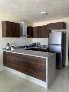 a kitchen with a large counter with a refrigerator at Departamento nuevo y céntrico con ambiente familiar en Guadalajara in Guadalajara