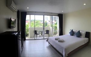 a bedroom with a large bed and a balcony at Glitter House in Phuket