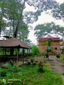 una cabaña con techo de paja y un edificio en Jaldapara Riverhine by StayApart, en Uttar Simlabari