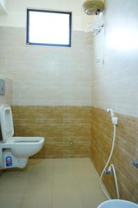 La salle de bains est pourvue de toilettes, d'un lavabo et d'une fenêtre. dans l'établissement Priya Woodz Homestay, Tirupati, à Tirupati