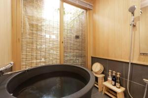 京都的住宿－ゲストハウス至の宿 Shibainu-Themed Guesthouse，带窗户的浴室内的黑色大浴缸