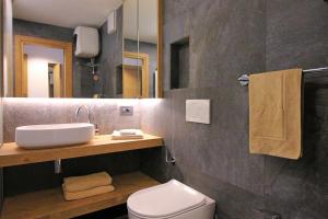 ein Badezimmer mit einem Waschbecken, einem WC und einem Spiegel in der Unterkunft ALPINE HOUSE - Dolomiti Affitti in Cavalese