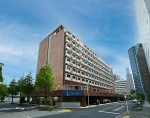 wysoki budynek z czerwonej cegły na ulicy miejskiej w obiekcie L stay＆grow晴海 w Tokio