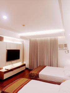 pokój hotelowy z 2 łóżkami i telewizorem z płaskim ekranem w obiekcie Cozy Suite Studio type condo in Matina Enclaves w mieście Davao
