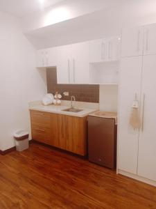 a kitchen with white cabinets and a sink and a refrigerator at Cozy Suite Studio type condo in Matina Enclaves in Davao City