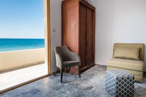 a room with a chair and a window with the ocean at Musela Studios in Episkopí- Rethimno