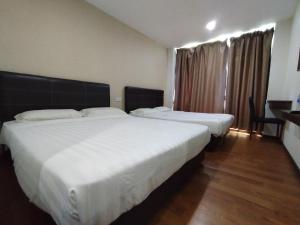 2 Betten in einem Hotelzimmer mit weißer Bettwäsche in der Unterkunft Super OYO 90668 Joy Inn in Miri