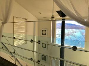 山中湖的住宿－Away From Noise,View Fuji Mt In The Designer House，一间设有玻璃楼梯的房间,设有窗户