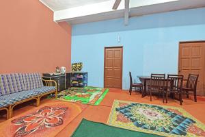 - un salon avec une table, des chaises et des tapis dans l'établissement Capital O 90664 Rabi Hotel, à Kota Bharu