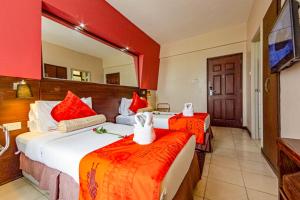a hotel room with two beds and a mirror at Hotel Rio in Nairobi