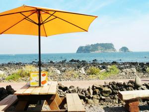 a picnic table with an umbrella on a beach at Hodo House in Seogwipo