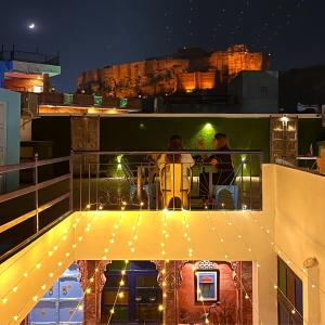 dos personas sentadas en una mesa en un balcón por la noche en Aura B&B - The Haveli Homestay en Jodhpur