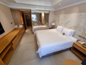 Habitación de hotel con cama blanca grande y TV en Pinegrove Hotel, en Gimhae