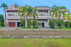 une grande maison avec des palmiers en face de celle-ci dans l'établissement OYO 91852 Prima Guesthouse Syariah, à Padang