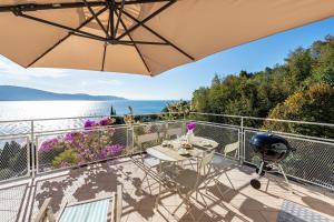 einen Balkon mit einem Sonnenschirm, einem Tisch und Stühlen in der Unterkunft Appartamento molini in casa Daria in Gargnano