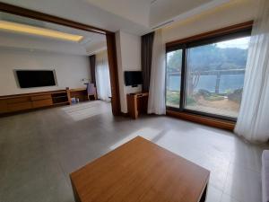 a living room with a tv and a large window at Pinegrove Hotel in Gimhae