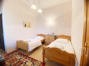 a bedroom with two beds and a dresser and a rug at Hotel Magdalena in Mtskheta