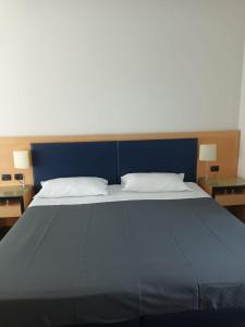 een groot bed met een blauw hoofdeinde en 2 tafels bij Luxury Rooms Padova Station in Padua