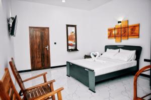 a bedroom with a bed and two wooden chairs at Aurum Boutique in Negombo