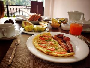 a plate of food with bacon and eggs on a table at Aurum Boutique in Negombo