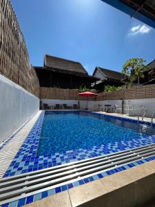 琅勃拉邦的住宿－Little Friendly Guest House and Swimming Pool，一座建筑物边的蓝色瓷砖游泳池