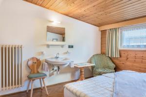 1 dormitorio con lavamanos, 1 cama y 1 silla en Villa Soldanella, en Ortisei