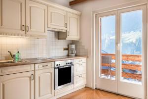 una cocina con armarios blancos y una ventana en Villa Soldanella, en Ortisei