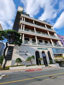 un bâtiment situé dans une rue avec un arbre en face de celle-ci dans l'établissement Pinegrove Hotel, à Gimhae