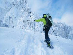 a person with a backpack standing on skis in the snow at Hotel Silk Inn Madarao in Iiyama