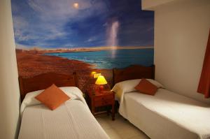 een kamer met 2 bedden en een schilderij van een regenboog bij Habitaciones Trovador in Puerto de Sagunto