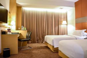 um quarto de hotel com duas camas e uma secretária em All Sedayu Hotel Kelapa Gading em Jacarta