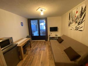 uma pequena sala de estar com um sofá e uma mesa em Poutran 2, studio 4 personnes au pied des pistes avec grande terrasse em Oz