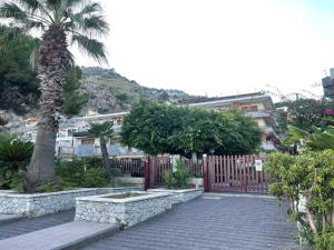 Una pasarela de ladrillo con una valla y una palmera en Incantevole appartamento Taormina, en SantʼAlessio Siculo