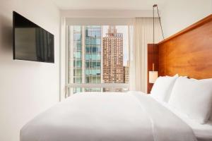 - une chambre avec un grand lit blanc et une grande fenêtre dans l'établissement Arlo NoMad, à New York
