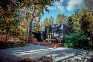 a black house in the woods with a gravel driveway at Strefa Relaksu Siemiany in Siemiany
