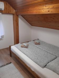 Łóżko w pokoju z drewnianym sufitem w obiekcie Portum vendégház w Siófoku