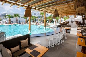 un complejo con una piscina con mesas y sillas en Smy Mediterranean White Santorini, en Kamari