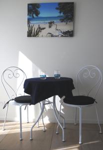 a table with two wine glasses and two chairs at Blue Birds in Oneroa