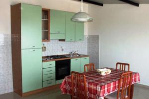 a kitchen with green cabinets and a table with chairs at Appartamenti Pirrera in Patti
