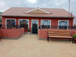 a red building with a bench in front of it at The Glamour House in Juja
