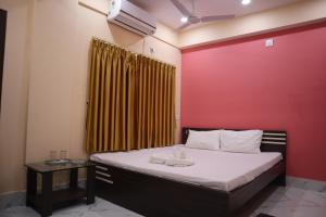 a bedroom with a bed with a red wall at Hotel Saan Berhampore in Baharampur