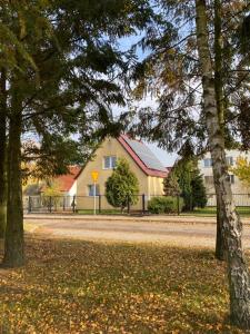 a house and trees in front of a street at Dom Na Zachodzie in Szczecinek