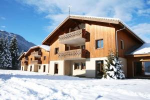 un bâtiment avec de la neige devant lui dans l'établissement Appartement cosy T3 4 à 6 pers avec Piscines Intérieure, Extérieure & Sauna à Samoëns en Haute-Savoie, à Samoëns