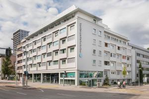 un grande edificio bianco all'angolo di una strada di VISIONAPARTMENTS Basel Nauenstrasse - contactless check-in a Basilea