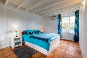 Schlafzimmer mit einem Bett mit blauer Bettwäsche und einem Fenster in der Unterkunft Villa bleue in Sanguinet