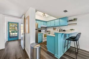 una cucina con armadi blu, tavolo e sedie di Remodeled Waterfront w Putting Green - Sleeps 10 a Lago Vista