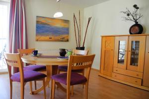 einem Esstisch mit lila Stühlen und einem Schrank in der Unterkunft Strandoase Whg 14 in Heringsdorf