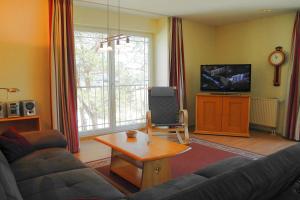 ein Wohnzimmer mit einer Couch, einem Tisch und einem Fernseher in der Unterkunft Strandoase Whg 14 in Heringsdorf