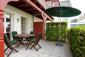 a table and chairs with a green umbrella on a patio at Vineta-App-02 in Heringsdorf