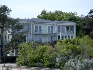 a large white house on a hill with trees at Strandoase-Whg-16 in Heringsdorf